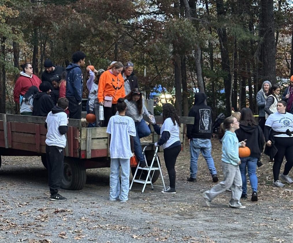 People returning from a hay ride with pumpkins